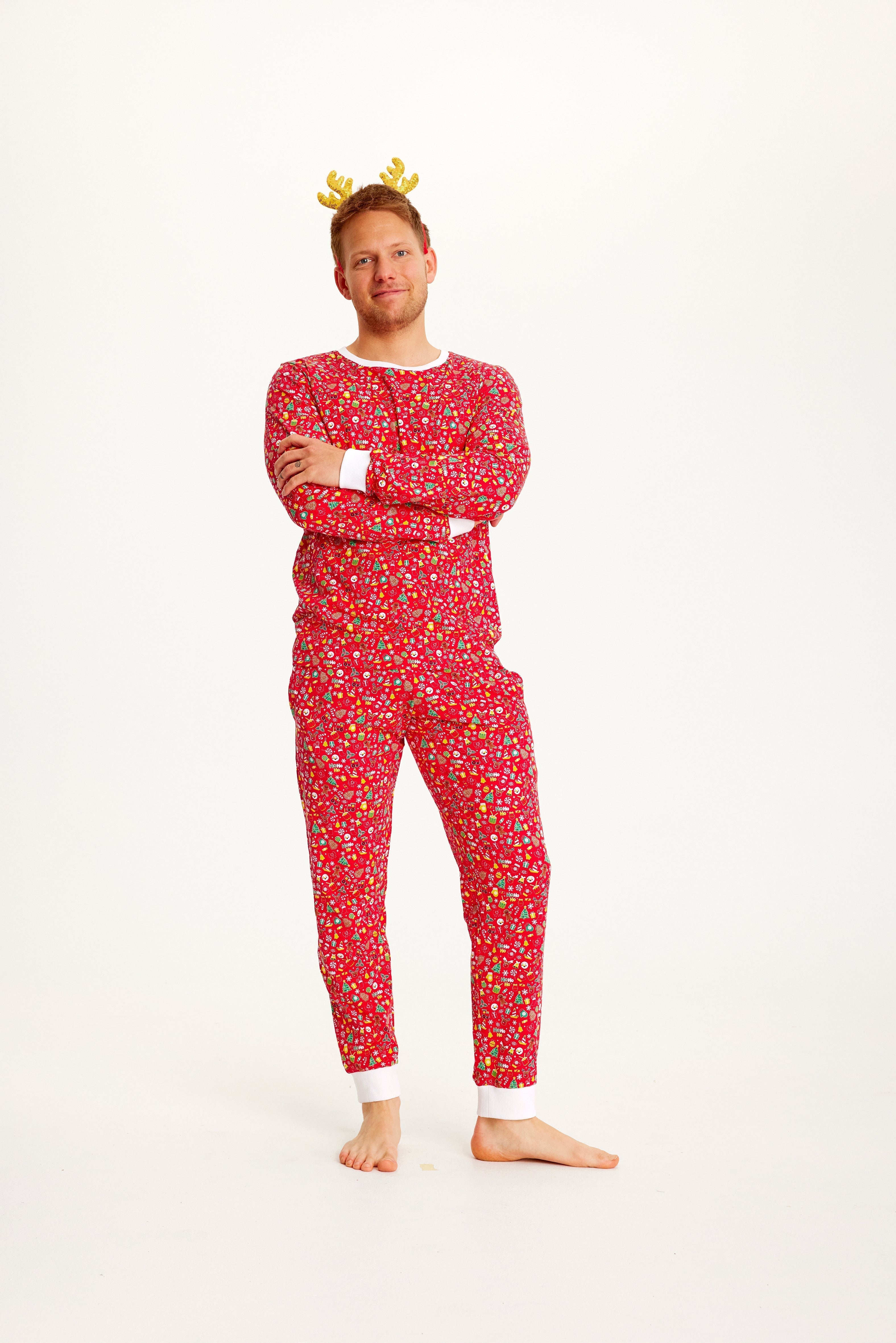 Un homme aux bras croisés portant un pyjama de Noël rouge.